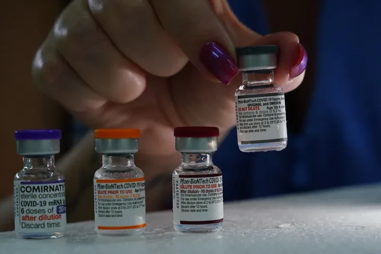 Mãos de enfermeira preparando vacina monovalente contra Covid-19 com seringa e frasco