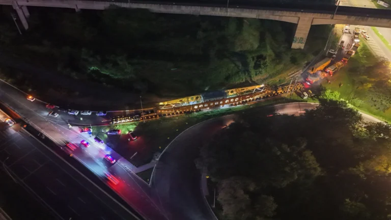 Comboio de transporte de carga gigante com transformador de 845 toneladas na Rodovia Carvalho Pinto à noite, com luzes de escolta.