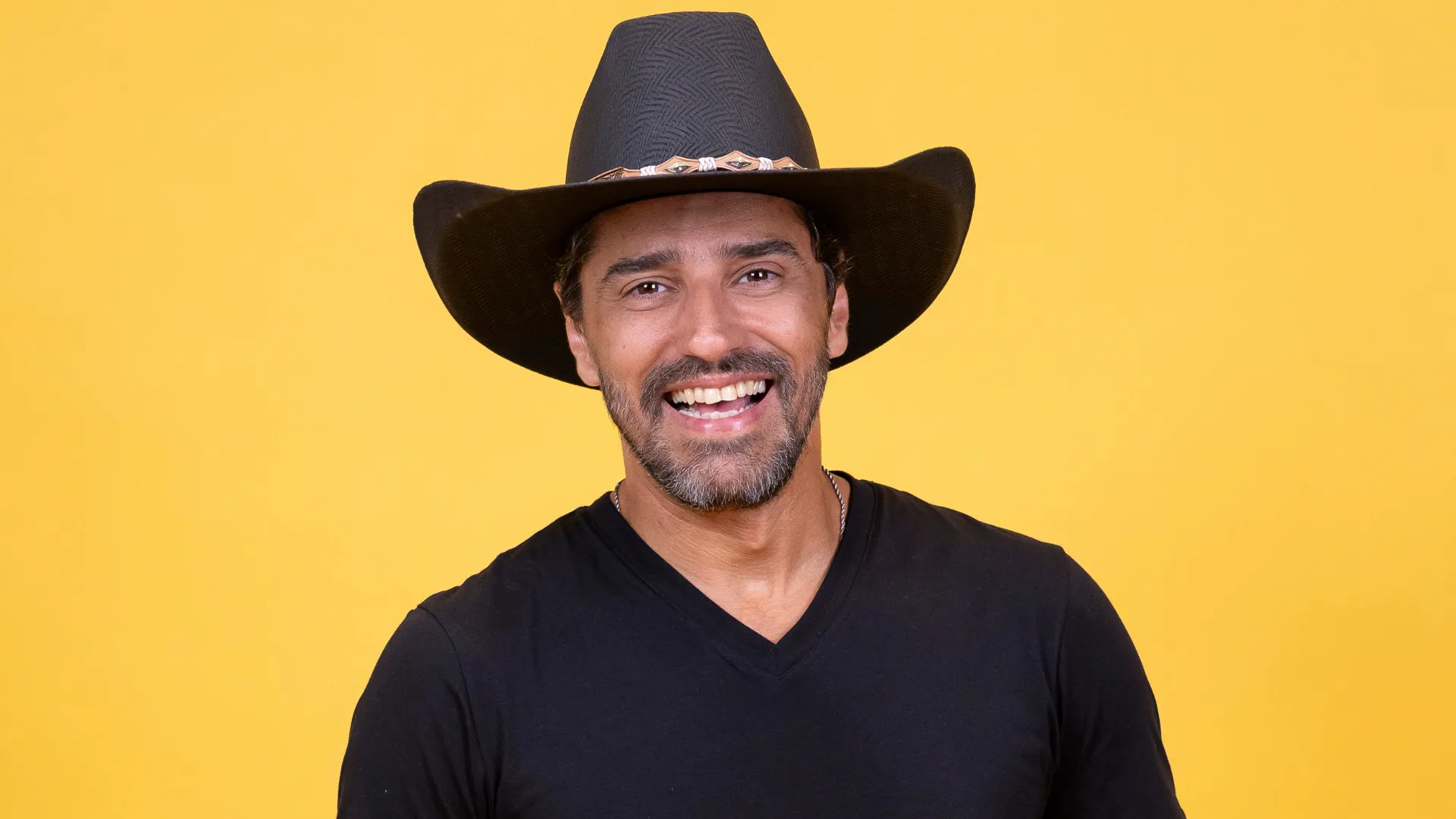Alberto Cowboy no palco com microfone, em show sertanejo