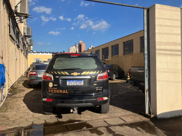 Distintivo da Polícia Federal em mesa com documentos sobre fraudes bancárias