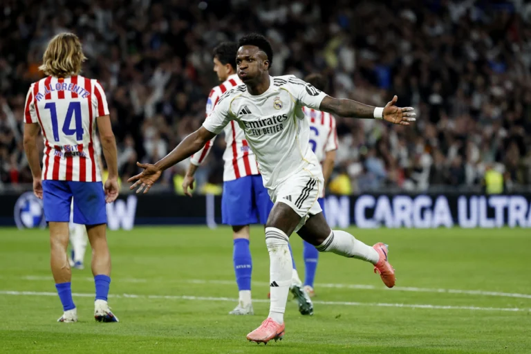 Vini Jr. comemorando gol, camisa do Real Madrid, campo de futebol