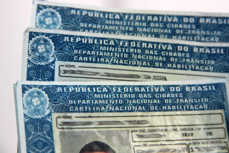 Pessoa feliz com CNH Social Paraná na mão, carro e moto ao fundo