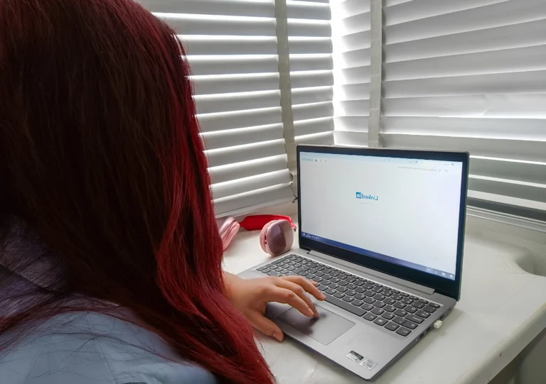 Mulher com expressão de cansaço na frente do computador, buscando emprego