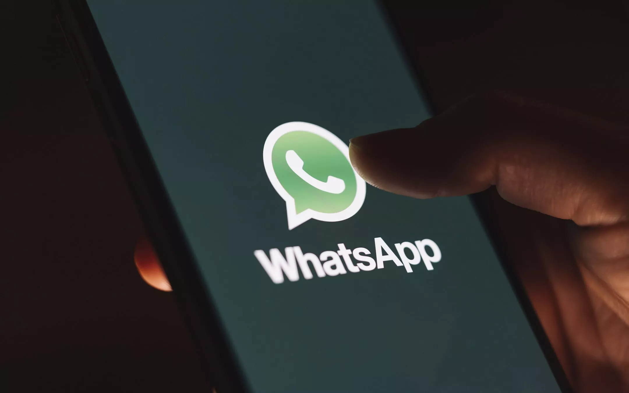 Homem olhando celular com WhatsApp, fundo de usina de cana