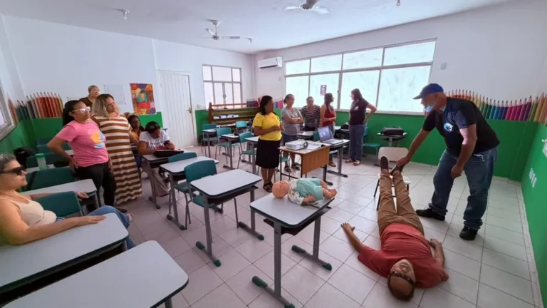 Grupo de professores de Carapebus em aula prática de primeiros socorros para emergências nas escolas, com instrutor enfermeiro.