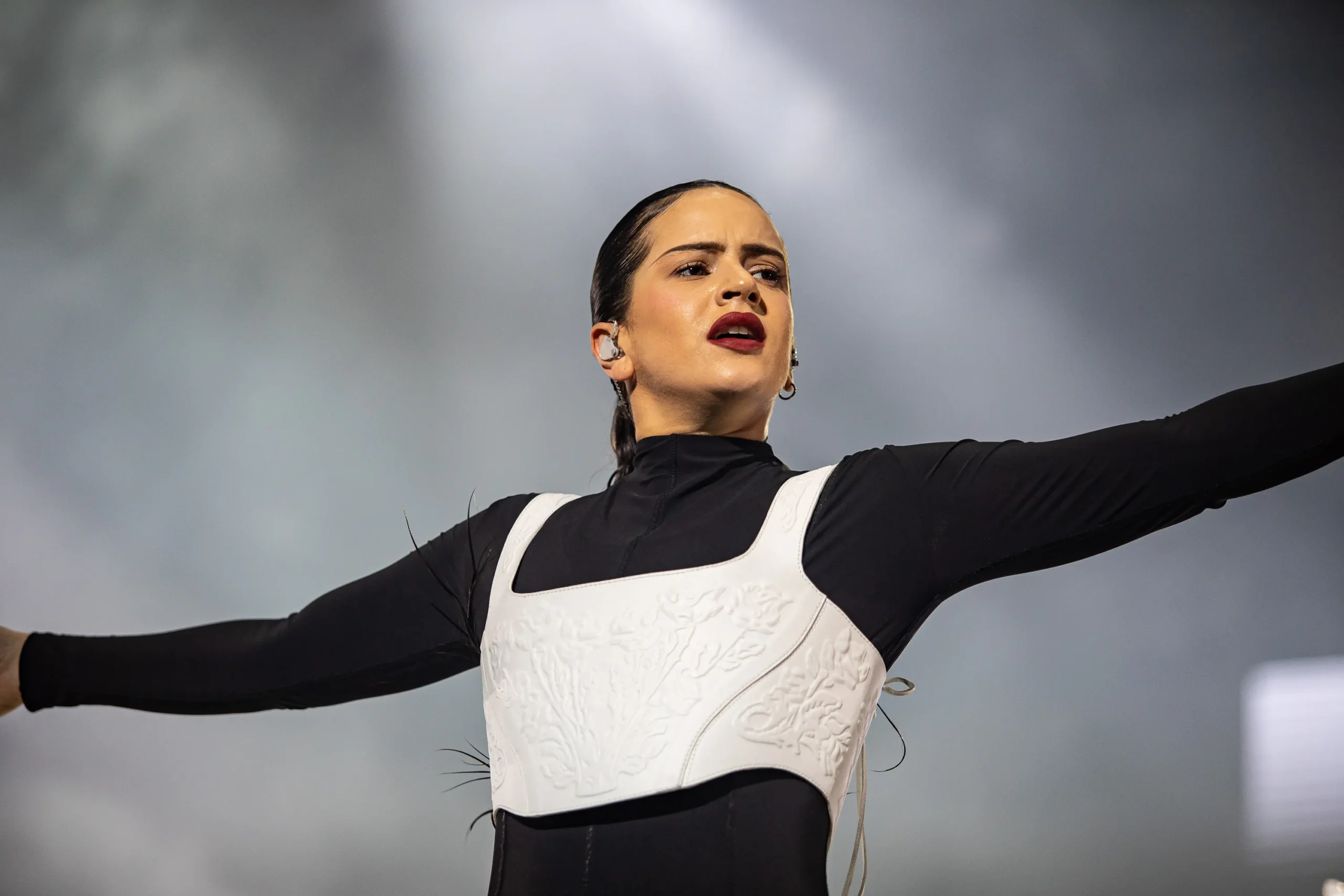 Rosalía no palco em Milão, segurando a barriga, visivelmente doente durante um show.