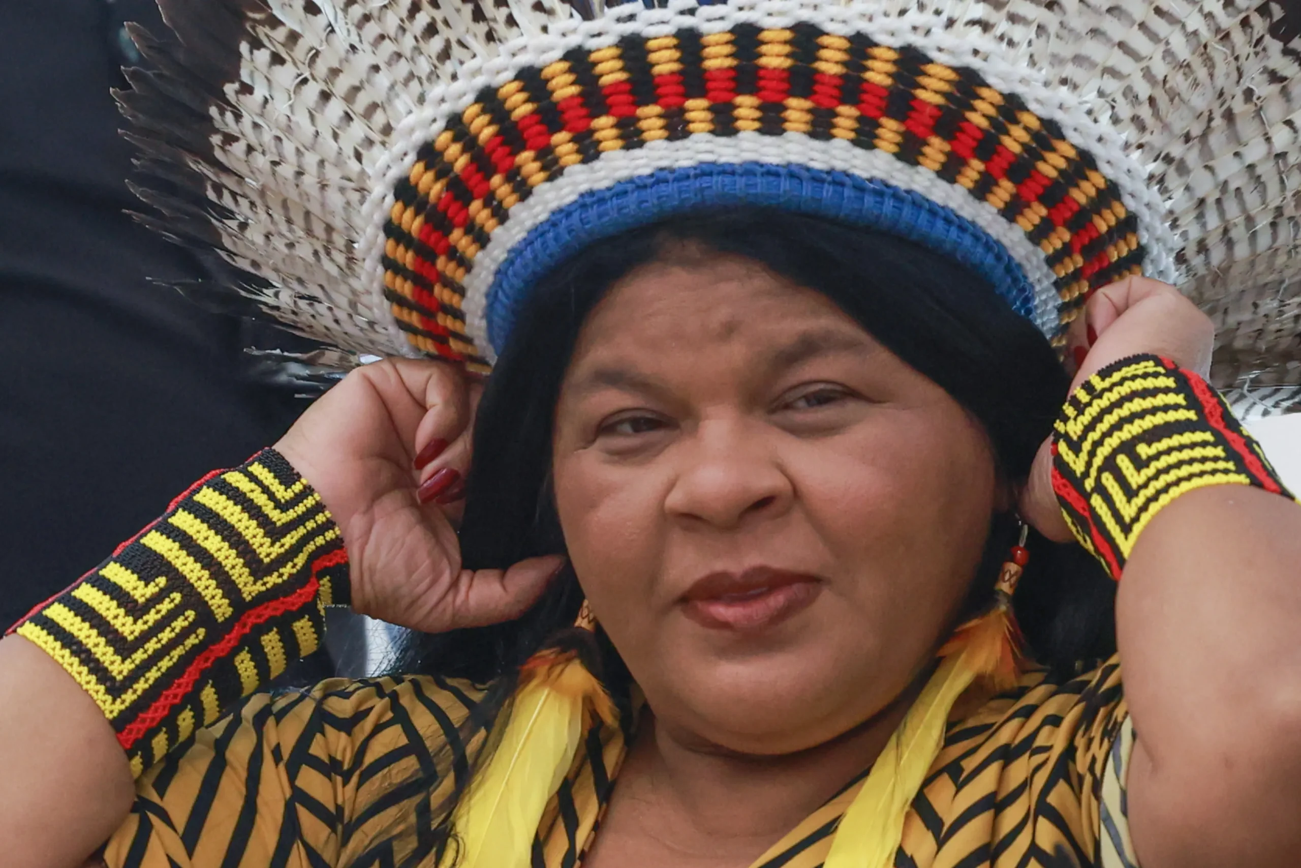 Ministra Sônia Guajajara em ambiente profissional, sorrindo, representando força e determinação.