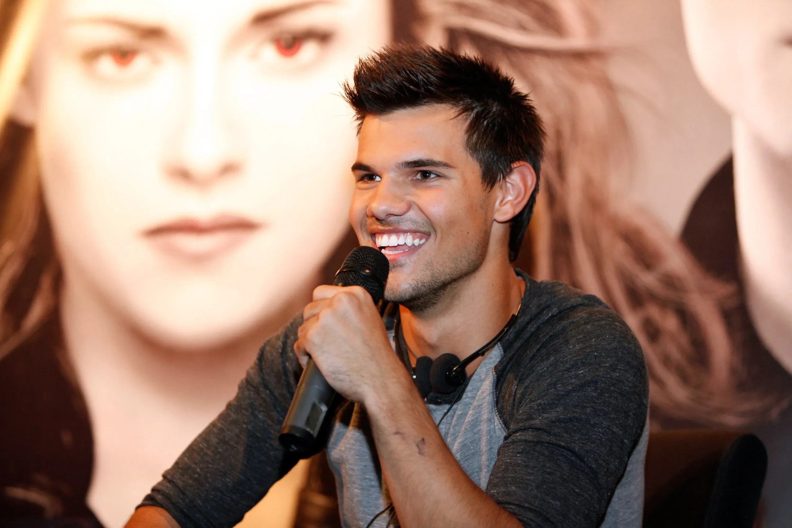 Taylor Lautner beijando a barriga da esposa enquanto seguram ultrassom