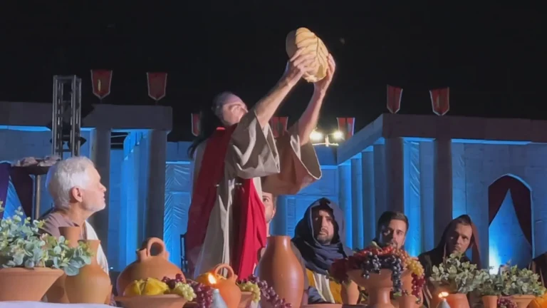 Encenação da Via Sacra em Ibitinga, com Jesus na cruz e multidão assistindo.