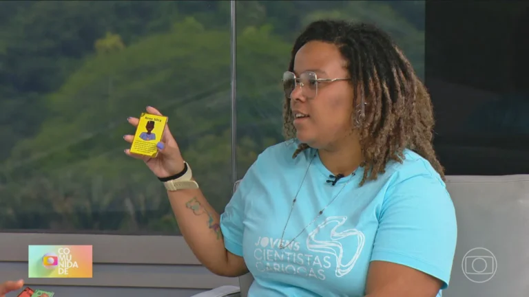 Thais Dias Xavier, mulher negra, segurando uma carta do seu jogo de combate ao racismo com imagem de personagem negro