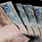 Mão segurando celular com app Meu INSS mostrando extrato do 13º salário para aposentados