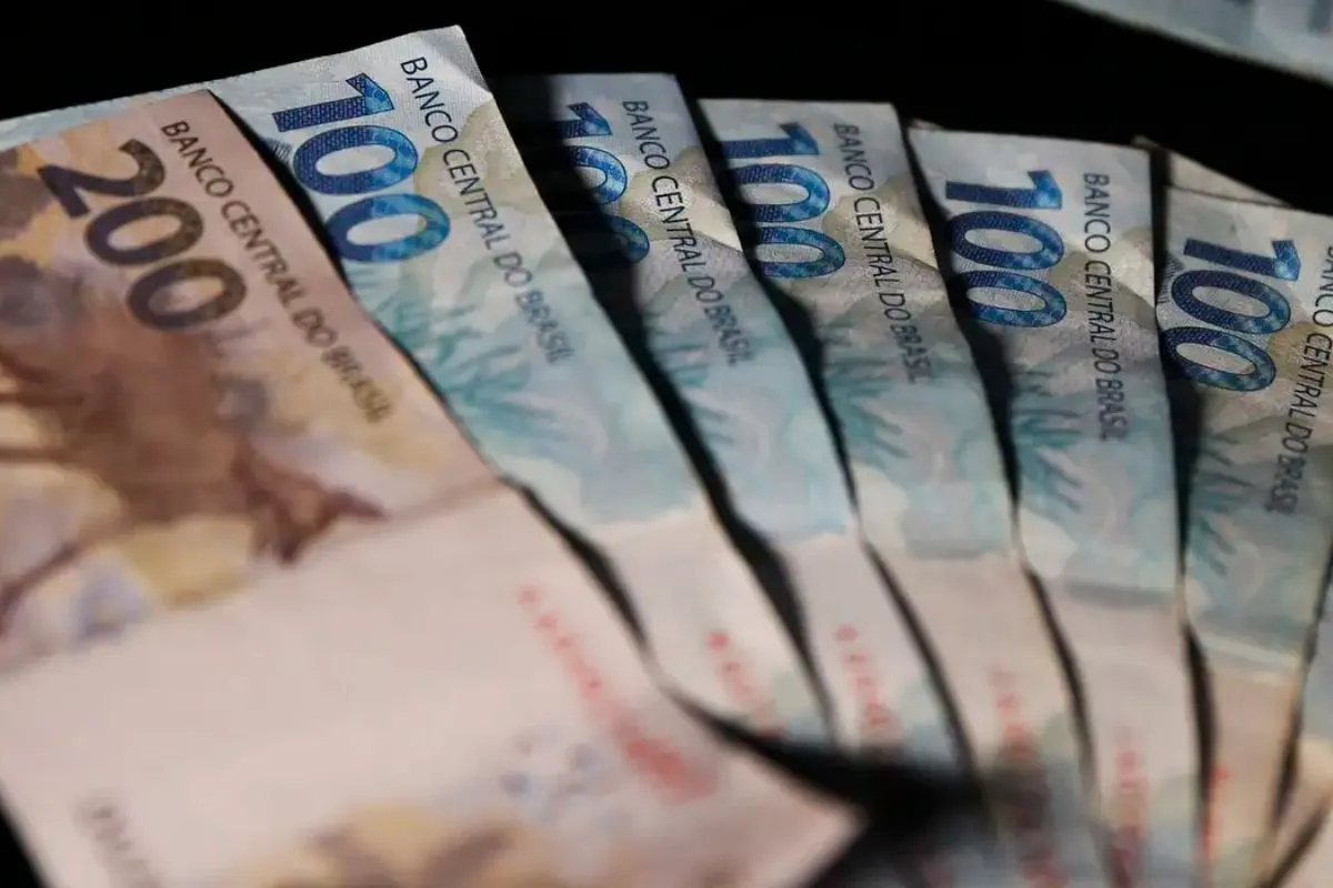 Mão segurando celular com app Meu INSS mostrando extrato do 13º salário para aposentados