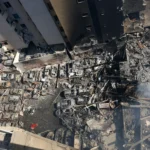 Ruínas de edifícios em Beirute após bombardeio israelense, equipes de resgate trabalhando.