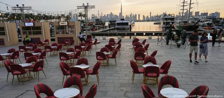 Dubai skyline com sinais do impacto da guerra, arranha-céus, luxo e desafios.