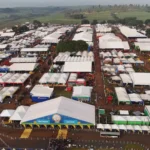 Vista panorâmica da Agrishow, com tratores, colheitadeiras e estandes ocupando uma grande extensão de terreno.