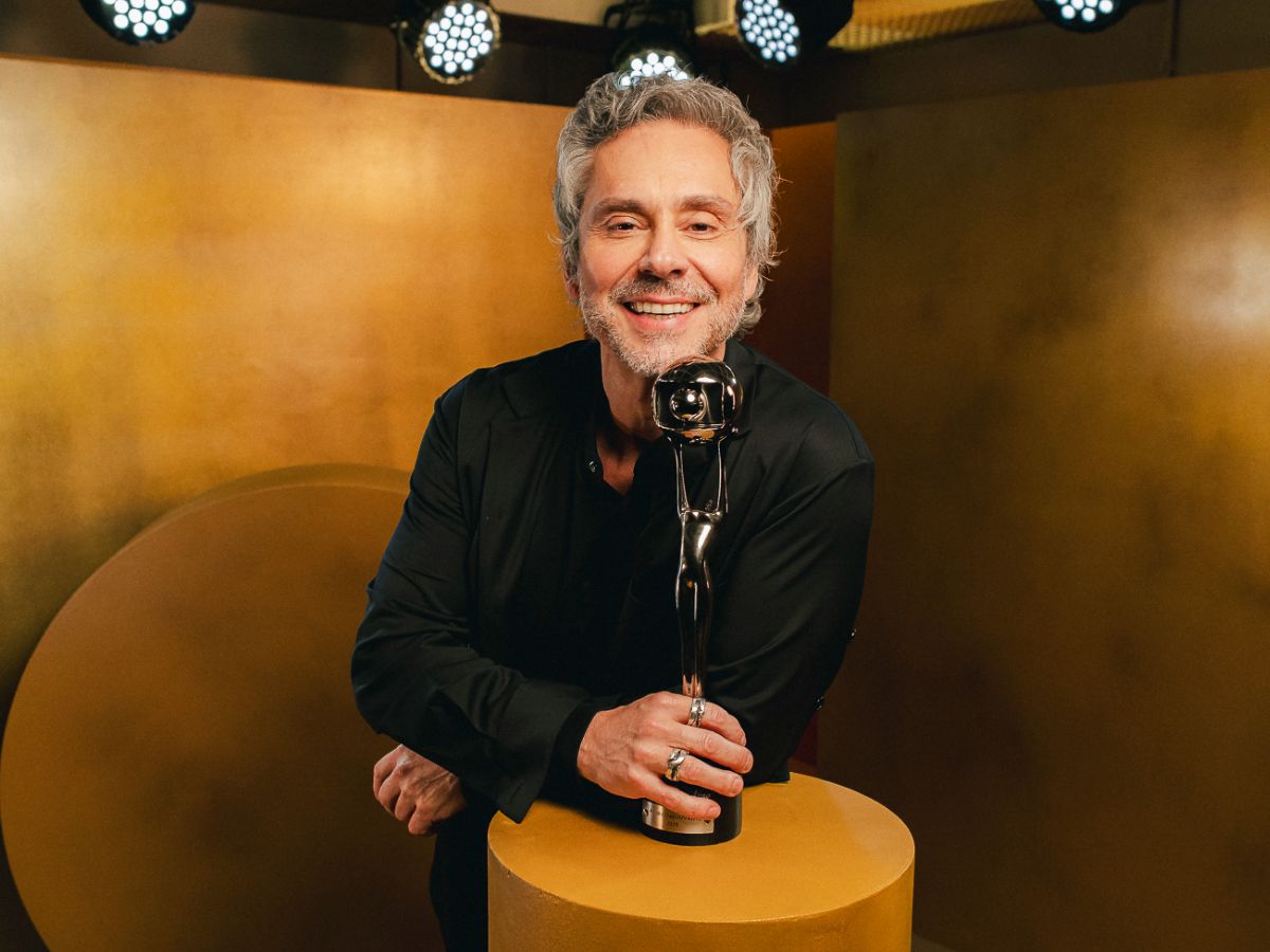 Ator Alexandre Nero no palco do Troféu Imprensa recebendo seu prêmio e revelando sua timidez ao público.