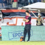 Jogadores do Corinthians em campo durante jogo do Brasileirão, com a bola em disputa e torcida ao fundo.