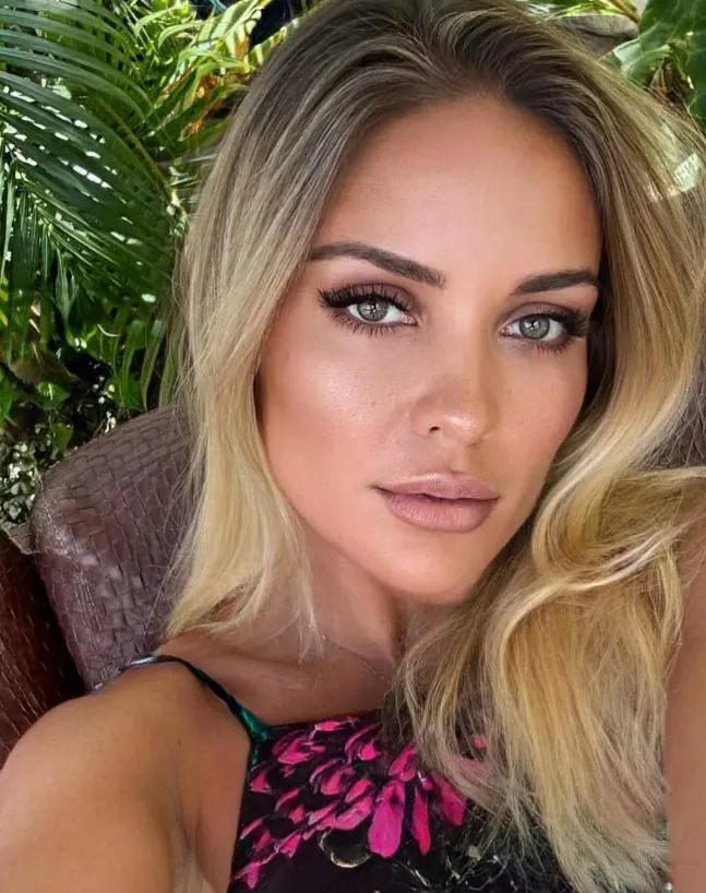 Atleta nadando em lago durante prova de Ironman no Texas, com barcos de segurança e outros competidores ao fundo.