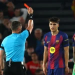 Árbitro István Kovács em campo, jogadores do Barcelona protestando contra decisão em jogo da Champions League contra Atlético de Madrid.