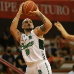 Dois jogadores de basquete, um com uniforme do Bauru e outro do Paulistano, disputam um rebote em quadra durante jogo do NBB.
