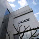 Fachada do prédio do Cade, com luzes e gráficos digitais sobrepostos, simbolizando a investigação sobre o Google e IA.