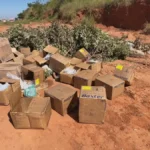 Materiais médicos descartados ilegalmente em rua de terra em Bauru, SP, mostrando seringas e caixas de medicamentos.