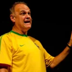 Oscar Schmidt em quadra, arremessando a bola de basquete, com sua camisa 14, durante uma partida.