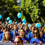 Grupo de pessoas caminhando em Petrópolis, com camisetas azuis, em evento de conscientização sobre autismo.