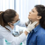 Pessoa apalpando o pescoço, procurando sinais de câncer de cabeça e pescoço