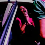 Homem algemado sendo escoltado pela polícia durante prisão de traficante