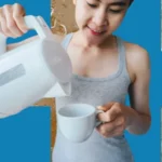 Mãos segurando uma caneca de água quente em um ambiente matinal tranquilo