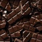 Barras de chocolate com percentual de cacau visível e grãos de cacau, representando a nova lei do chocolate no Brasil.