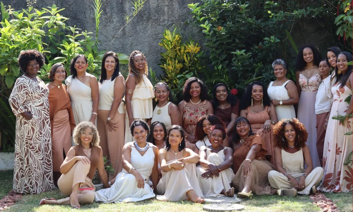 Grupo de mulheres negras autoras sorrindo e apresentando seu livro "Vozes Escreviventes" no estande 14 da Bienal do Livro da Bahia.