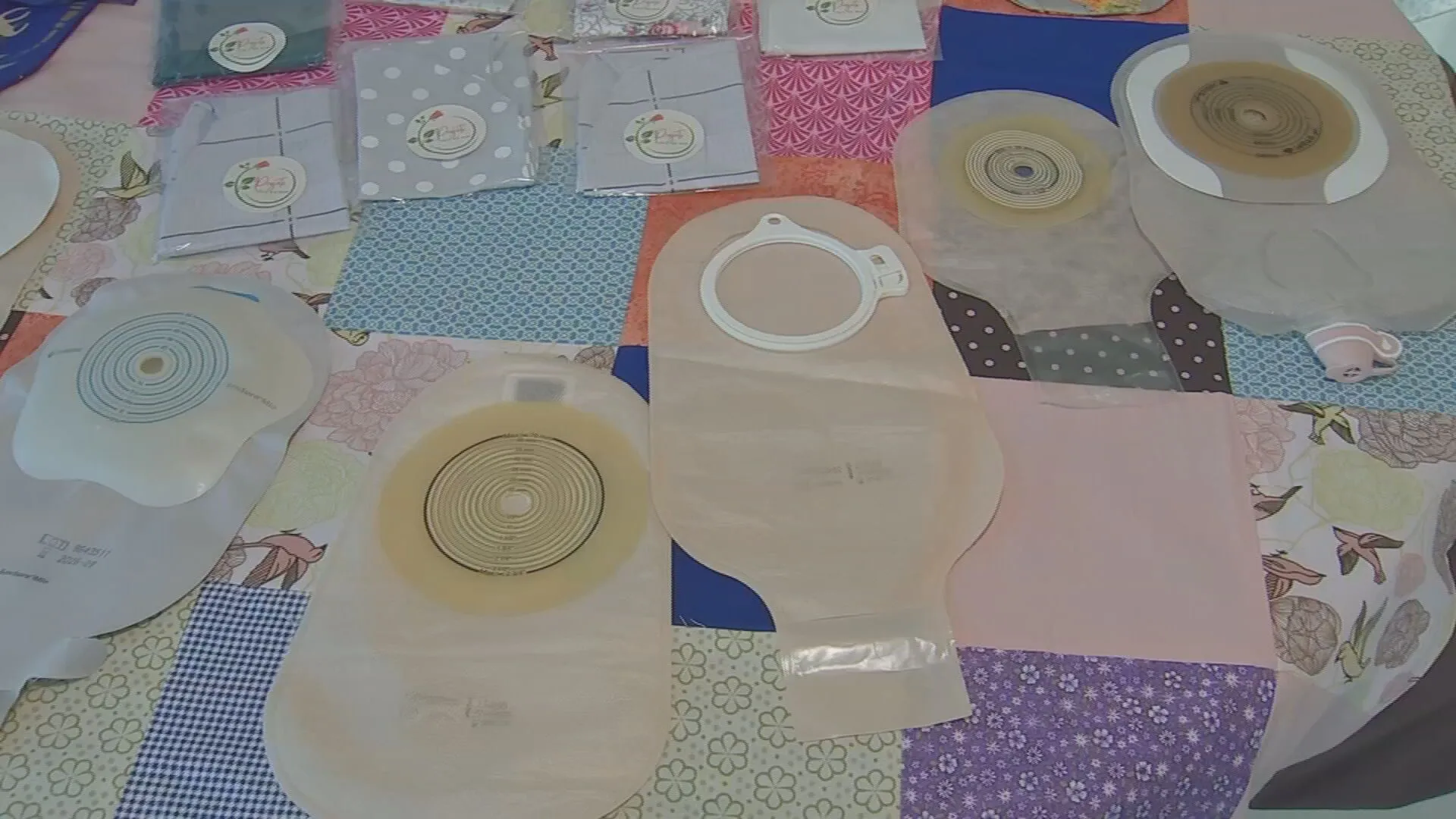 Mãos de voluntárias costurando capa colorida para bolsa de ostomia