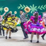Dançarinos de quadrilha com trajes típicos e cenários dos enredos no Arraial de Belô 2026