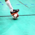 Partida de futsal da Copa TV Grande Rio com jogadores em movimento e bola em jogo