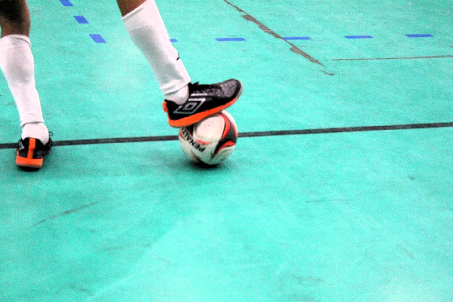 Partida de futsal da Copa TV Grande Rio com jogadores em movimento e bola em jogo