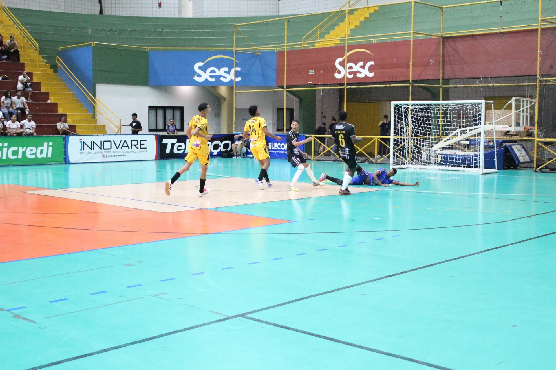 Partida de futsal juvenil da Copa TV Grande Rio em Petrolina com jogadores correndo atrás da bola em quadra.