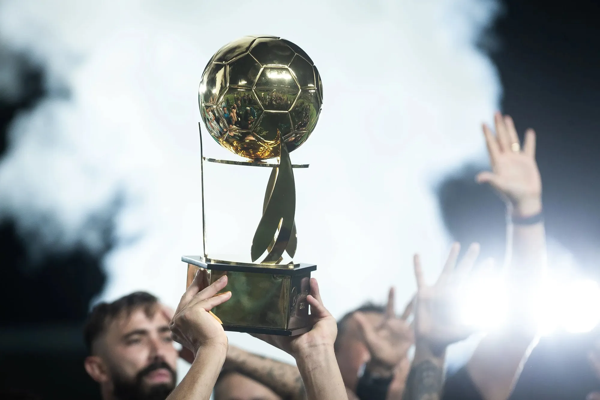 Troféu verde da Copa Verde com fundo de campo de futebol