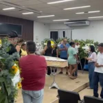 Velório de Ana Luiza Mateus, candidata a miss, em caixão cercado por flores em Teixeira de Freitas, Bahia.