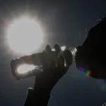 Homem, mulher, criança e idoso bebendo água e usando protetor solar em um dia de tempo seco em Jundiaí