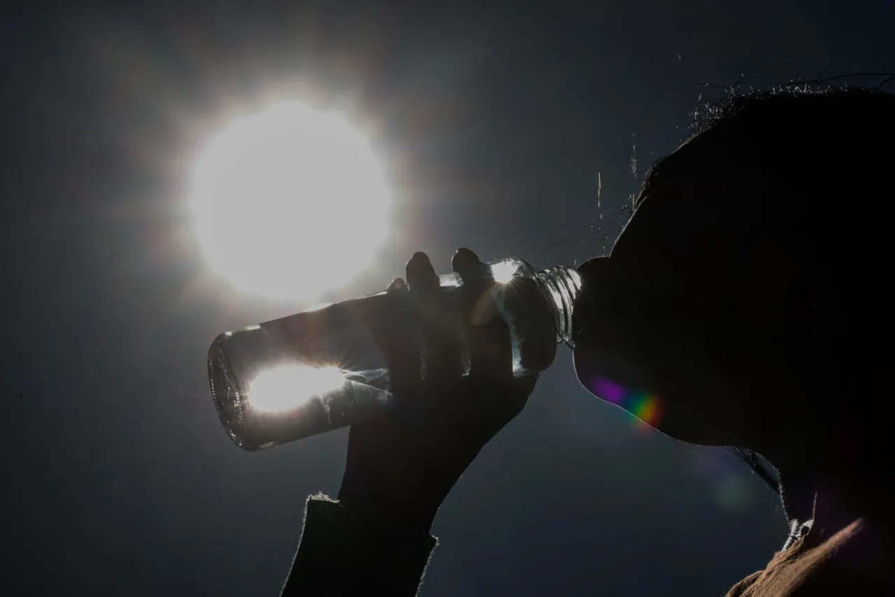 Homem, mulher, criança e idoso bebendo água e usando protetor solar em um dia de tempo seco em Jundiaí