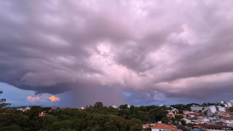 Ruas de BH com alagamento após fortes chuvas, pessoas com guarda-chuvas e carros passando com dificuldade