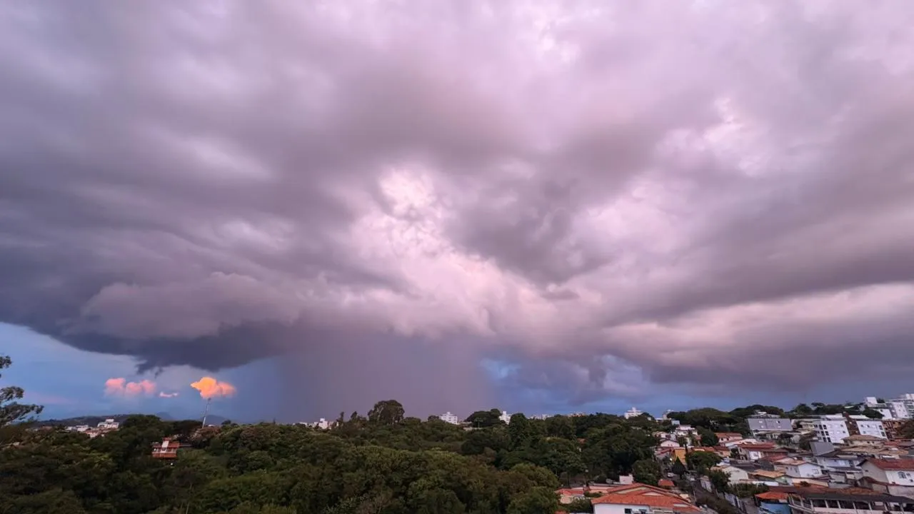 Ruas de BH com alagamento após fortes chuvas, pessoas com guarda-chuvas e carros passando com dificuldade