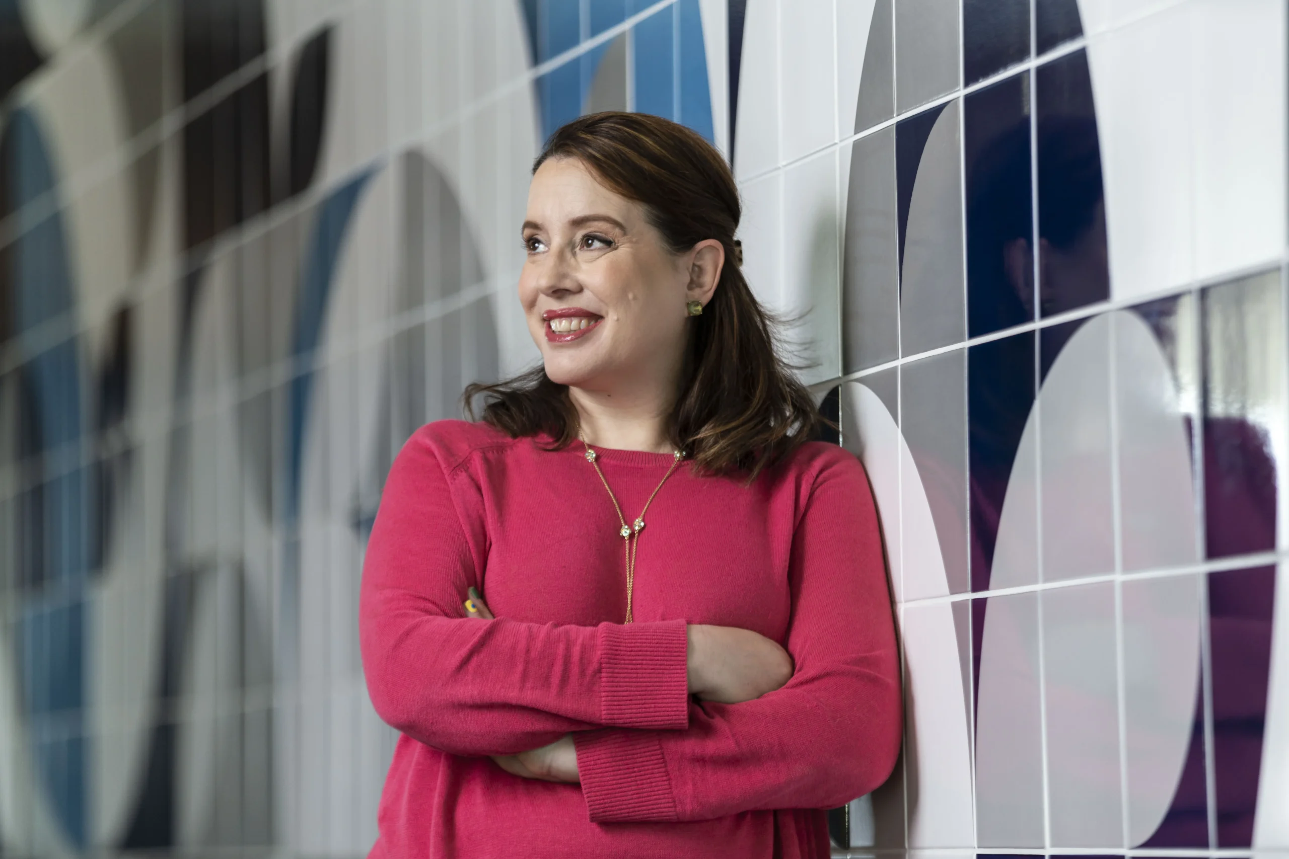 Julia Quinn, autora de Bridgerton, sorrindo e autografando livros para fãs em um estande na Bienal do Livro Bahia.