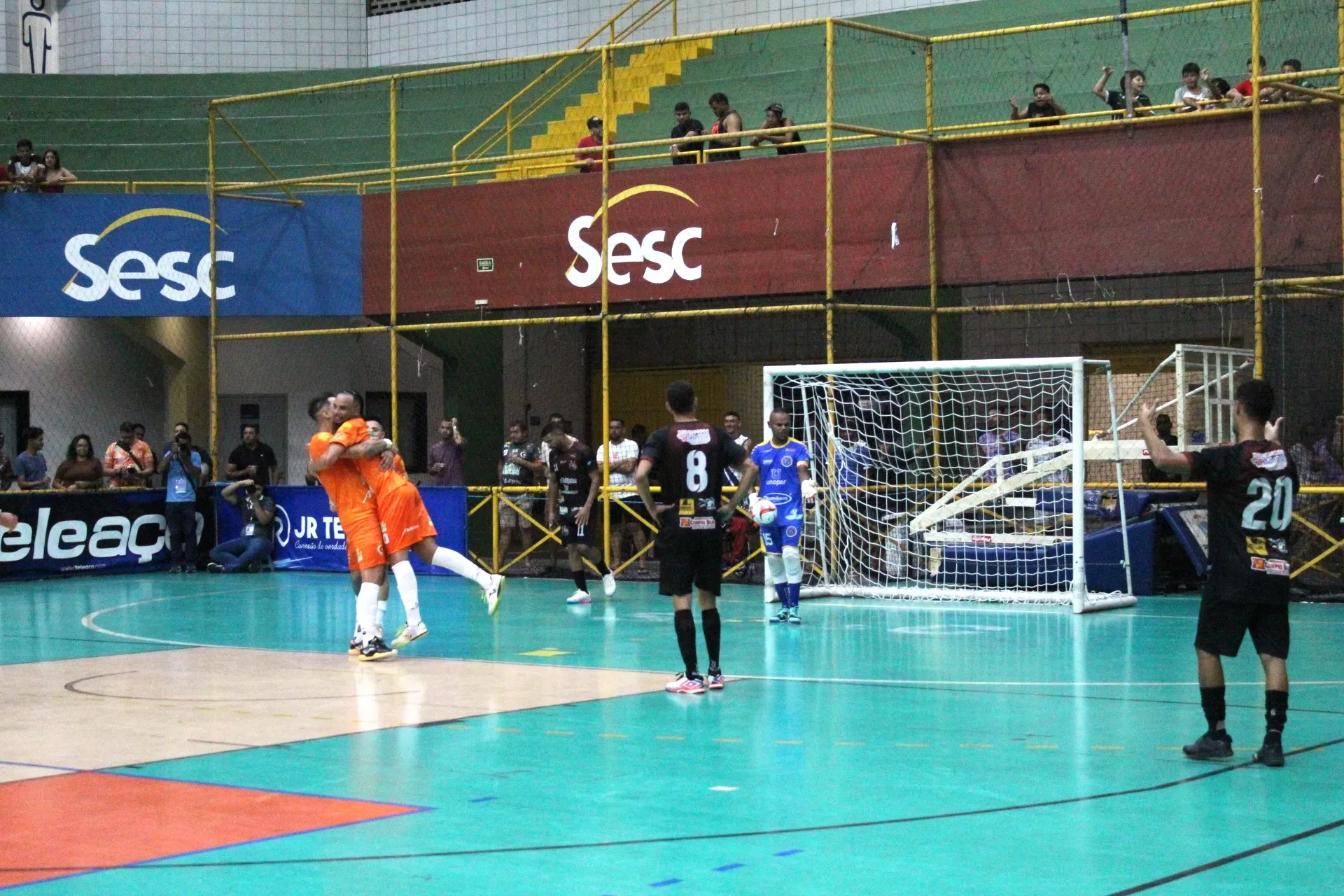 Dois jogadores de futsal disputando a bola em quadra, com um deles finalizando para o gol, durante a Divisão Especial Futsal.