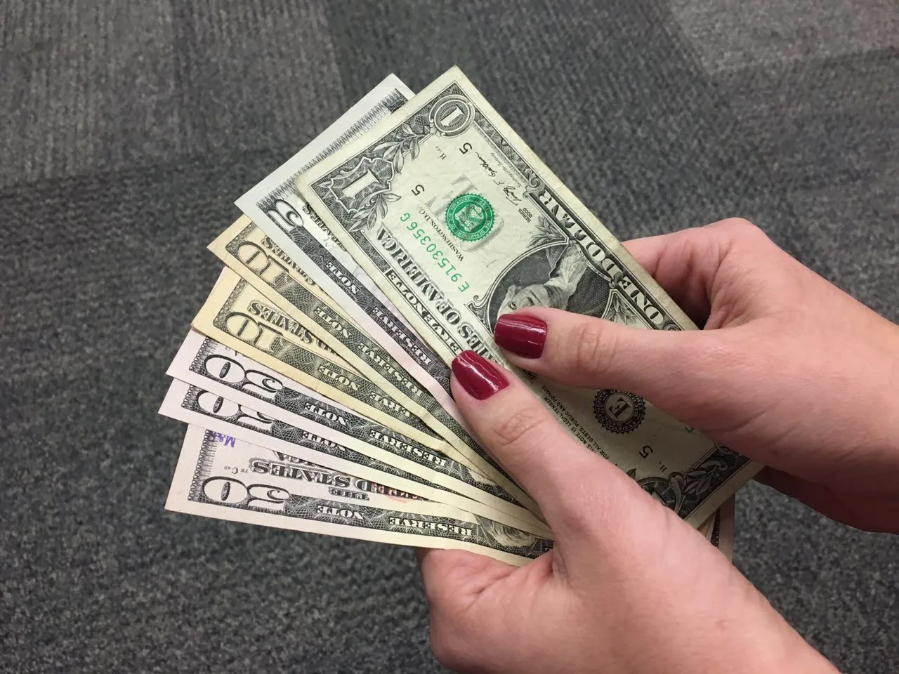 Pilhas de dólares e reais com gráficos financeiros e um mapa do Oriente Médio ao fundo, ilustrando a influência de conflitos globais no preço do dólar.