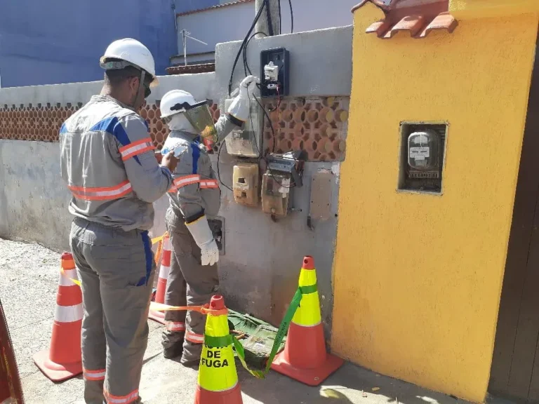 Técnicos da Enel Rio inspecionando medidores e fiação elétrica em Duque de Caxias para identificar furto de energia