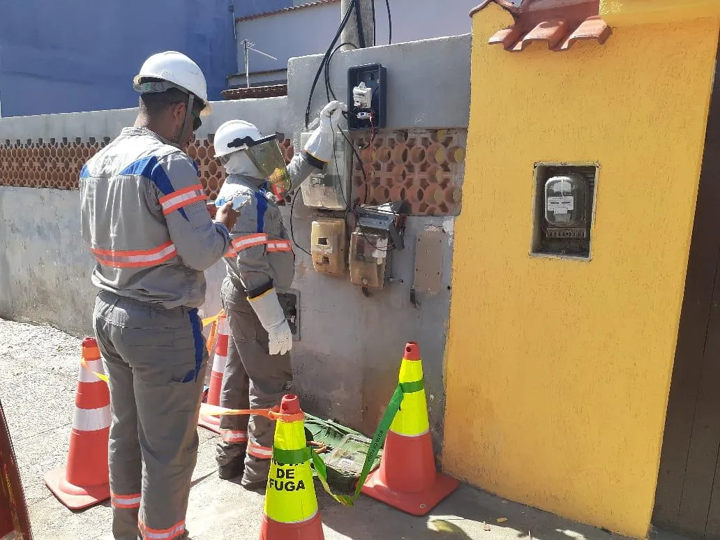 Técnicos da Enel Rio inspecionando medidores e fiação elétrica em Duque de Caxias para identificar furto de energia