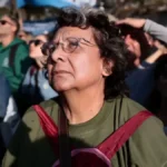 Homem ou mulher com expressão de preocupação, com documentos e contas à frente, representando a pobreza do trabalhador argentino.